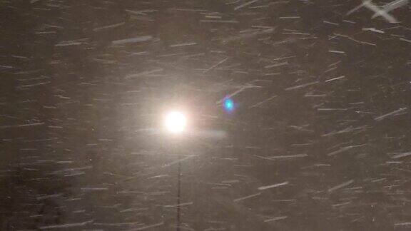 在路灯的灯光下雪花飘落的动态视频季节性暴风雪暴风雪圣诞夜城市街道上大雪纷飞寒风凛冽下雪了冬天的雪花