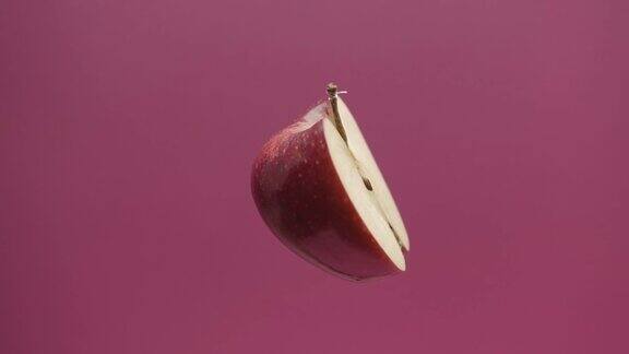 一个美丽可口的苹果切成两半在红色背景上旋转