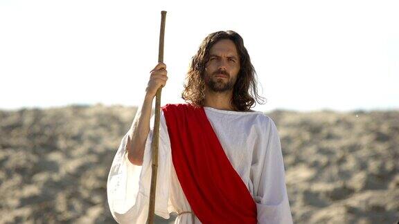 耶稣拿着木杖站在沙漠中宣讲基督教信仰的转变