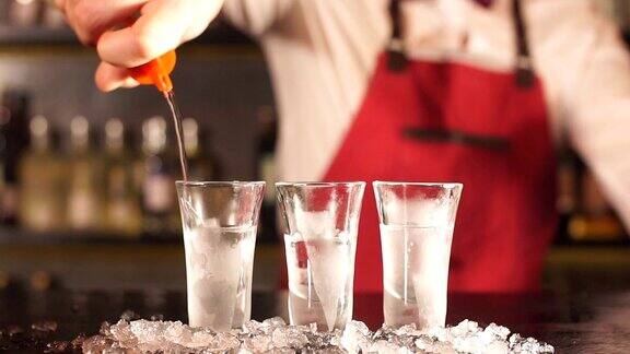 专业的酒吧服务员在优雅的制服倒伏特加在磨砂短玻璃杯