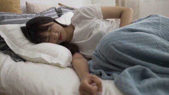 亚洲妇女在家里的卧室里忍受着月经疼痛蜷缩在床上抱着自己的肚子