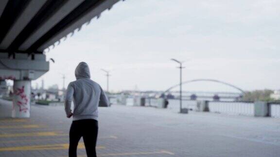 在桥下跑步运动的人的运动帽衫的后视图