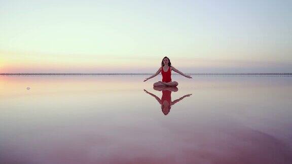在乌克兰粉红色的盐湖上做瑜伽的女人