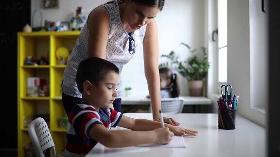 男孩在老师的帮助下写作和学习