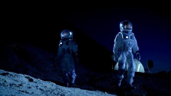 两名宇航员穿着宇航服探索新发现的行星在背景空间基地太空殖民的未来概念