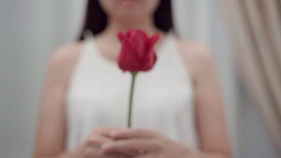 女人手里拿着一朵花一束红玫瑰放在自己面前