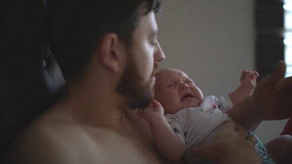 爸爸在家里照顾他刚出生的儿子而婴儿在哭泣