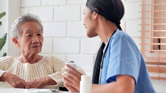 亚洲老年妇女听年轻的黑人女护士医生解释药物给她年长的女性病人在家采购产品医疗护理护理退休志愿者慈善教育养老院在家照顾者医药和卫生保健