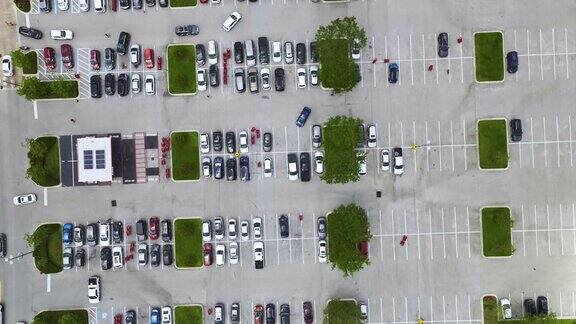许多五颜六色的汽车停在停车场上的鸟瞰图上面有停车地点和方向的线条和标记