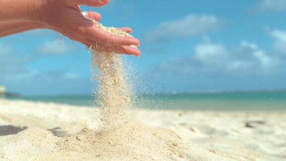 慢镜头:温柔的夏日风从女人的手中吹出白沙