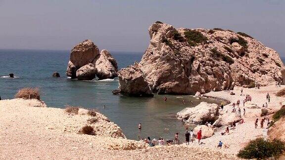 人们在塞浦路斯岛上的一个小沙滩上沐浴和晒太阳这里是阿芙罗狄蒂的诞生地礁石从海水中伸出来地中海的美丽沙滩岩石沙滩