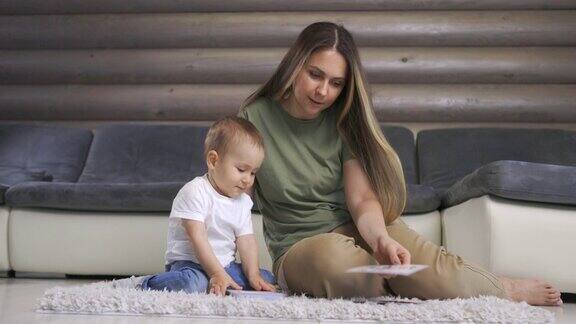 快乐的年轻妈妈和宝宝在家里温暖的地板上玩字母卡片在家早教