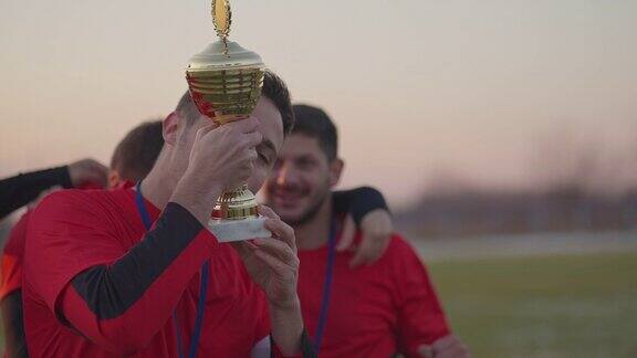 冬天的一天足球队在球场上庆祝赢得了足球奖杯