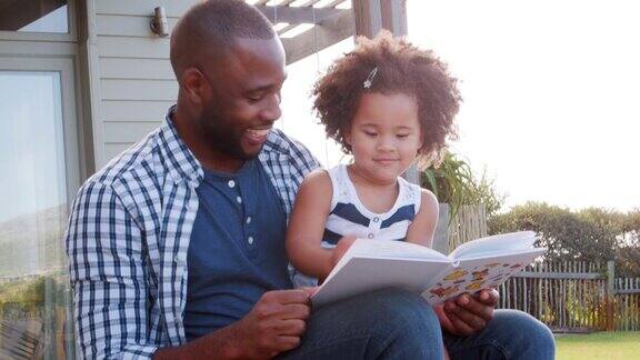 黑人父亲和小女儿在户外读书