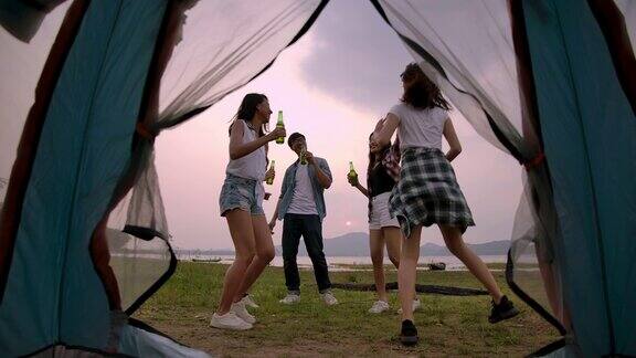 慢镜头4K一群朋友在露营旅行中唱歌和喝啤酒