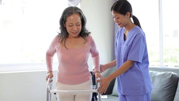 护士正在帮助一位老年妇女学习用拐杖走路理疗师为练习走路的老年妇女做理疗