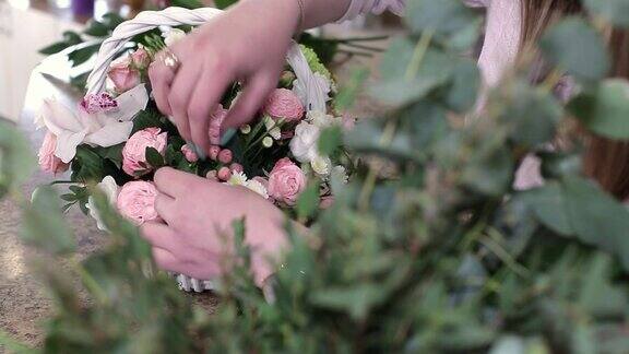 年轻女子花商制作美丽的花花束玫瑰在白色的篮子