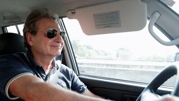 快乐的退休老人握着方向盘在高速公路上驾驶4K