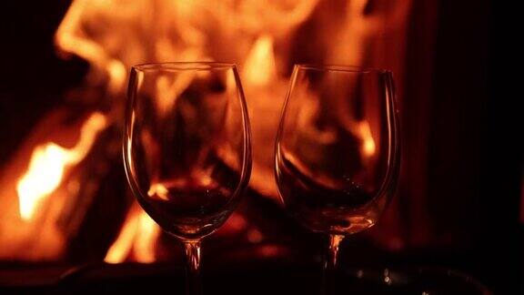 两杯酒在壁炉熊熊燃烧的火焰下两个空酒杯温暖舒适的壁炉和背景上的火焰