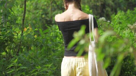 在阳光明媚的日子里女士沿着绿色的森林景观散步
