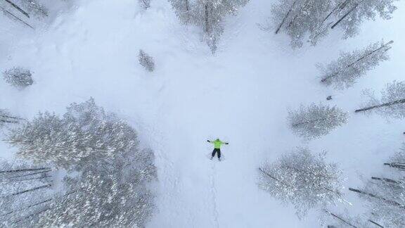 空中的快乐微笑的女孩在雪山的新雪中制作雪角