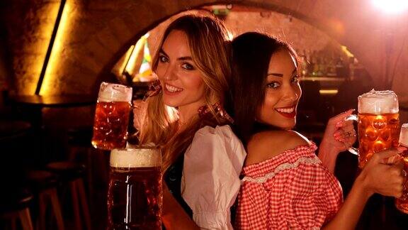 身着巴伐利亚服饰的年轻多民族妇女用啤酒庆祝啤酒节