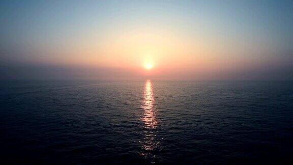在平静的海面上从移动的巡洋舰的开放甲板上看到日落和日出