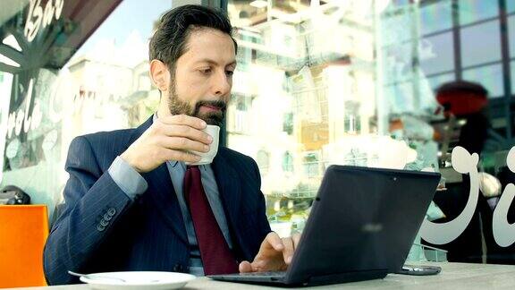 喝咖啡和用笔记本电脑工作的商人:喝咖啡