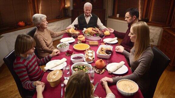 一家人在感恩节餐桌上手拉手祈祷