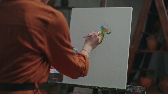 女艺术家在画架上画彩色的图画