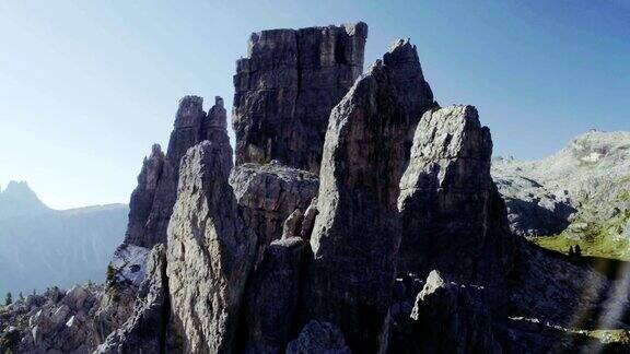 在阳光明媚的日子里在松石嶙峋的山顶上空飞行夏季户外山地探险之旅旅行探索阿尔卑斯山白云石五托里意大利4k无人机轨道视频