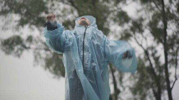 快乐的白人男孩的肖像跳跃和欢呼雨在户外可爱的白人学生穿着雨衣玩在雨天的夏天童年的快乐