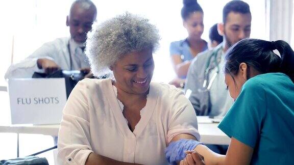 志愿护士准备给女性注射流感疫苗