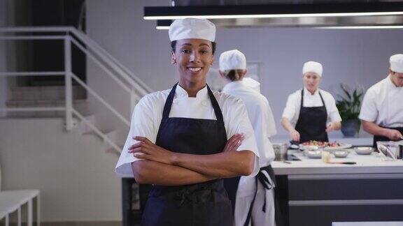 非裔美国女厨师在一家餐馆的厨房里工作看着镜头微笑着