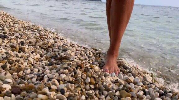 女人赤脚走出大海走在鹅卵石上