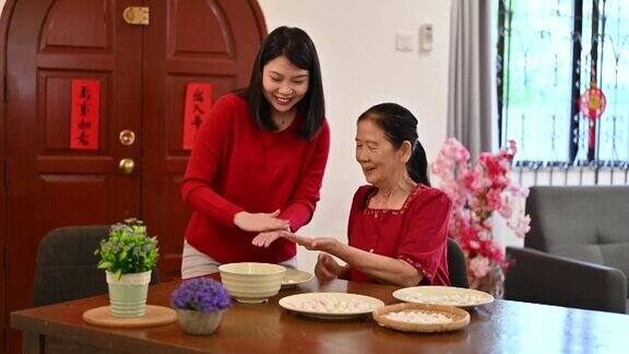 一位亚洲的奶奶和她的孙女正在为庆祝中国新年而准备汤圆