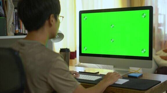 年轻人在家里用绿色屏幕的电脑键盘打字