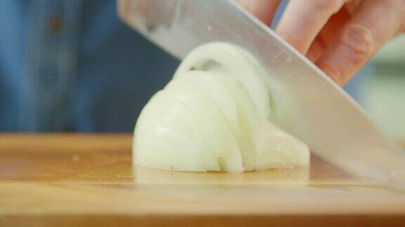 男人的手在切菜板上切洋葱的特写