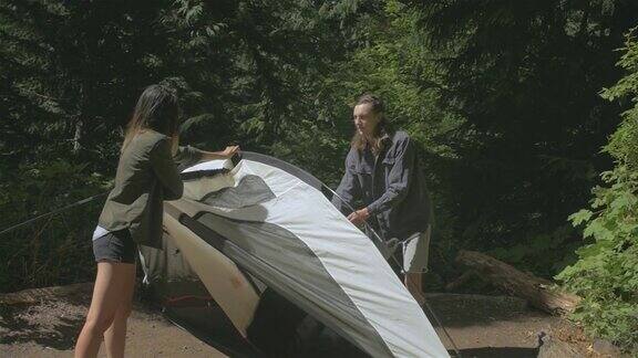 一对年轻的异族夫妇在国家森林公园里一起搭帐篷
