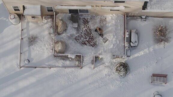 一个成年人在冬天下雪后用铲子清理门廊上的积雪鸟瞰图直接在无人机视频上方