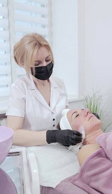 美容师用湿纸巾擦拭妇女脸上的皮肤