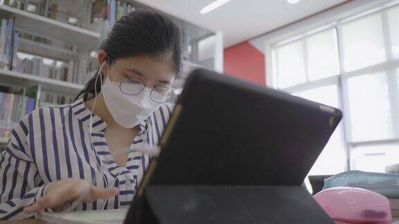 亚洲女孩戴着防护面具在图书馆工作