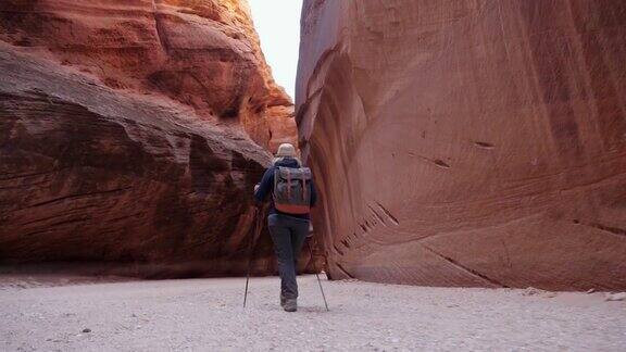 游客徒步行走在带有橙色岩层的狭缝峡谷的沙漠上