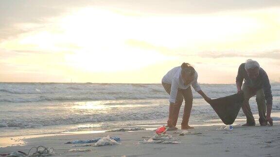 一对亚洲老夫妇用装满垃圾的塑料袋清理海滩缓慢的运动生态安全概念4k决议
