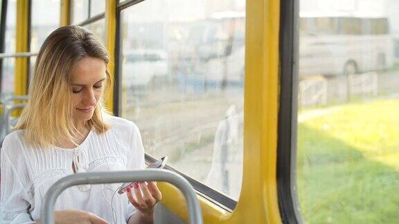 一个漂亮的女孩在电车里用智能手机听音乐