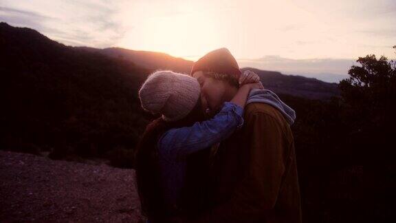 浪漫的多民族情侣在日落时亲吻在山顶