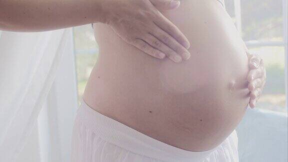 孕妇慢慢的抚摸着自己的肚子