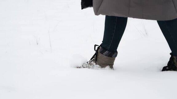 一个女人脚上穿着冬靴慢慢地走在雪地里在寒冷的天气里独自行走在冬天散步