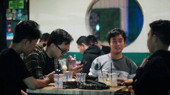 一群年轻人在晚上的咖啡馆里用手机聊天