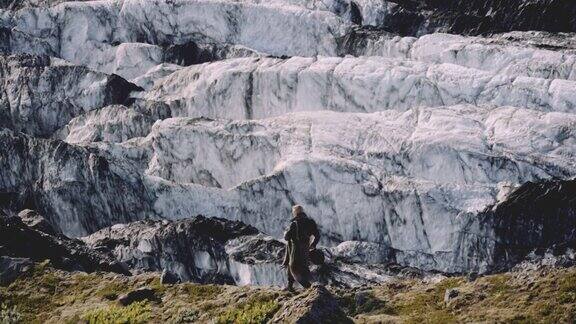 旅行者沿着冰川旁边的岩石山脊行走